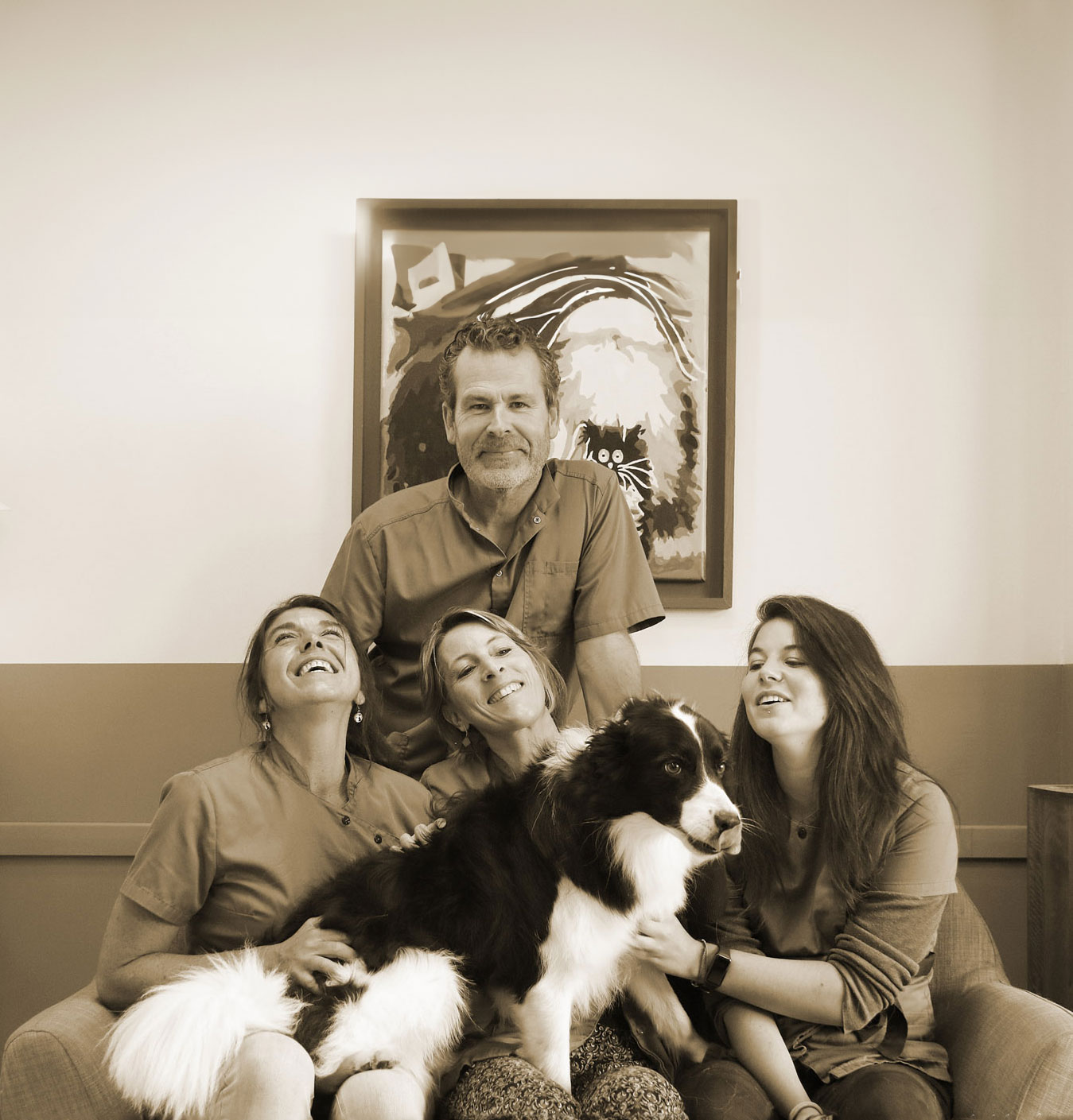 Portrait format paysage de l'équipe du cabinet vétérinaire Vet Atao à Plomeur avec un chien sur les genoux de 3 des professionnelles du soin animalier. Cette image a été modifiée (complétée) via l'IA générative de Photoshop.